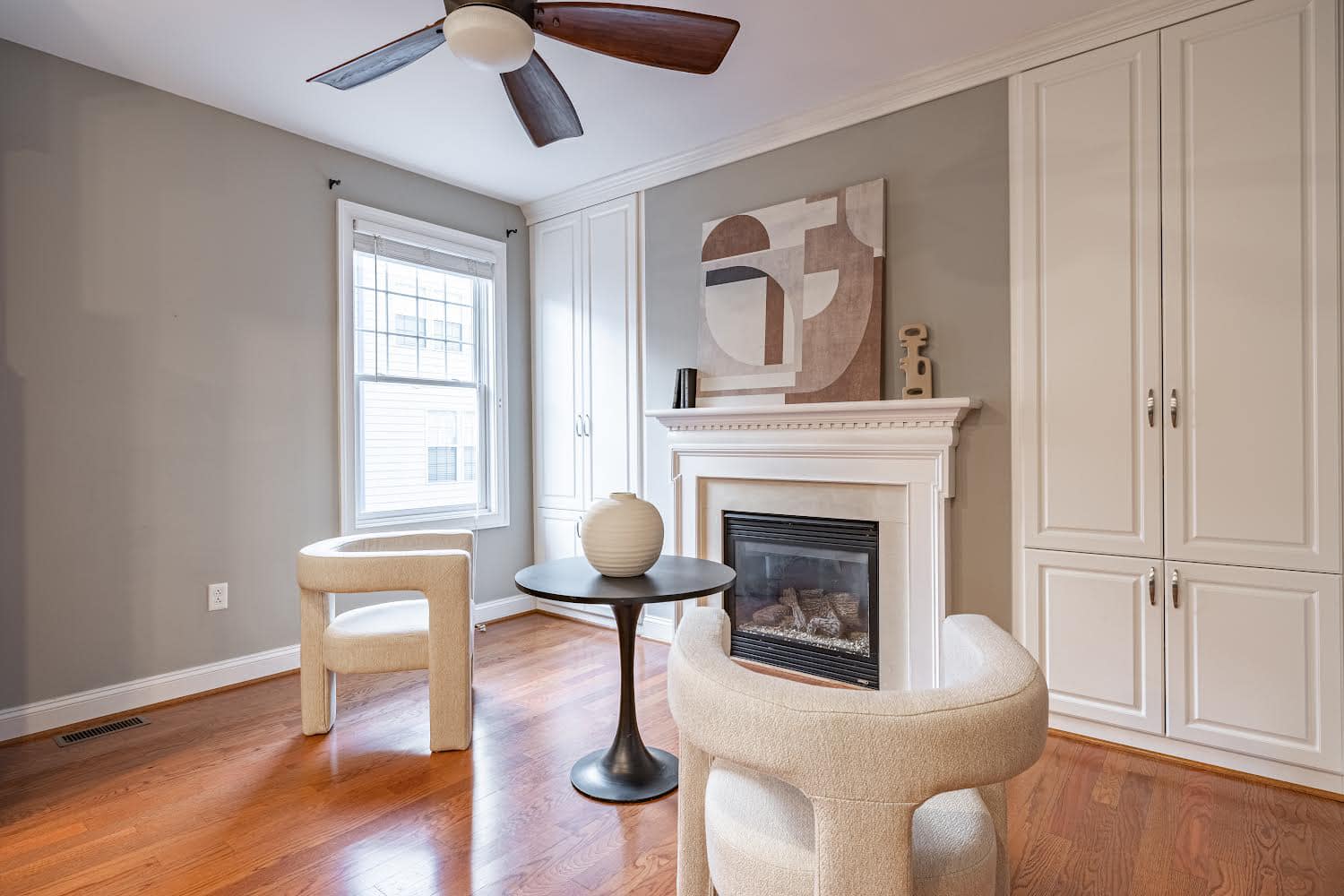 Staged living room with fireplace, abstract art and cream accent chairs — Richmond VA home staging